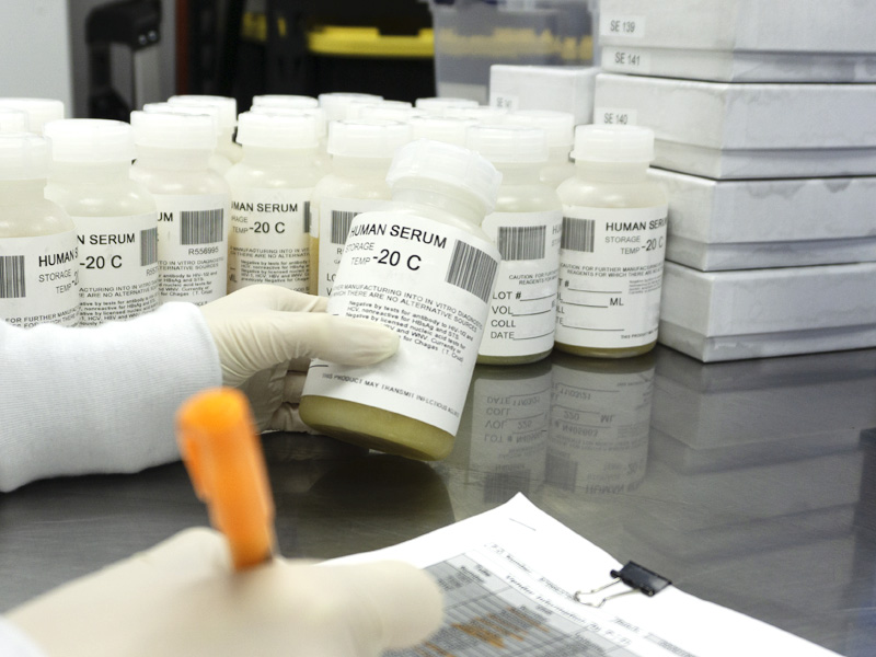 cantor bioconnect lab technician taking notes with orange pen while holding human serum sample